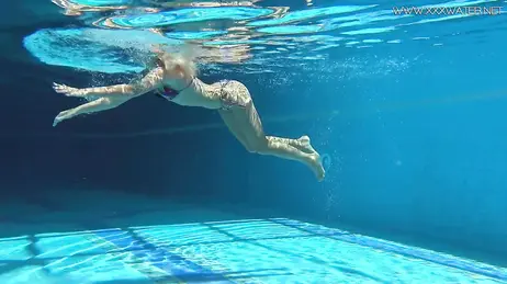La vue d'une bombe en bikini string plongeant dans la piscine